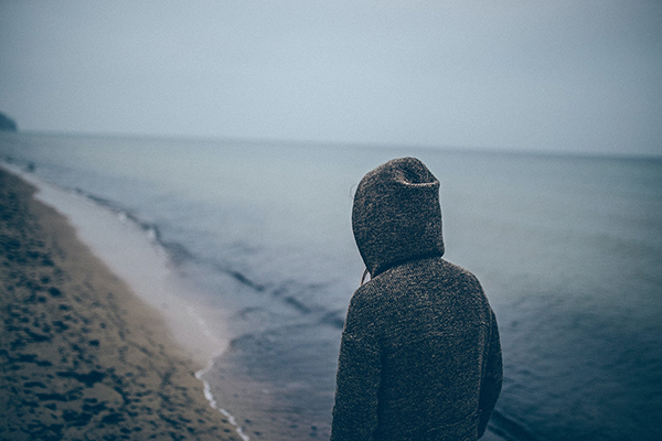 Personne avec capuche marchant le long de la mer